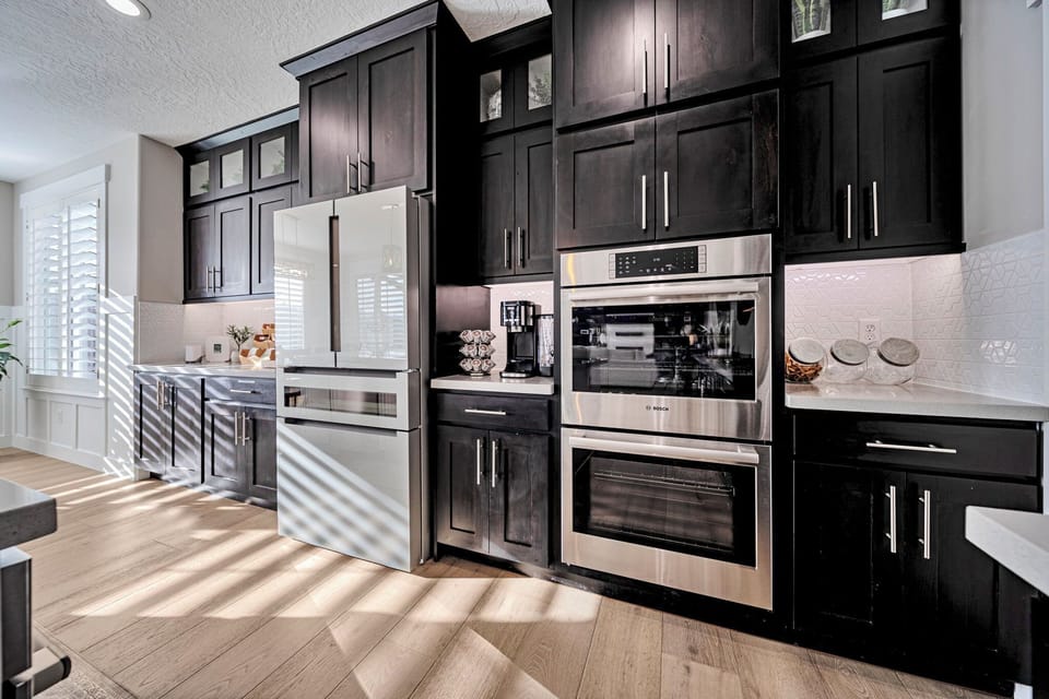 Bright designer kitchen with double ovens and stylish dark cabinetry