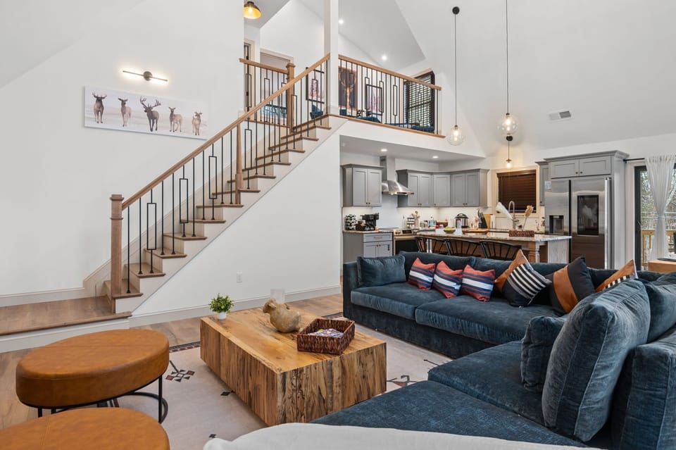 From this angle, the spacious layout ties together the living room, kitchen, and dining area, showcasing the inviting sectional and warm wood accents.