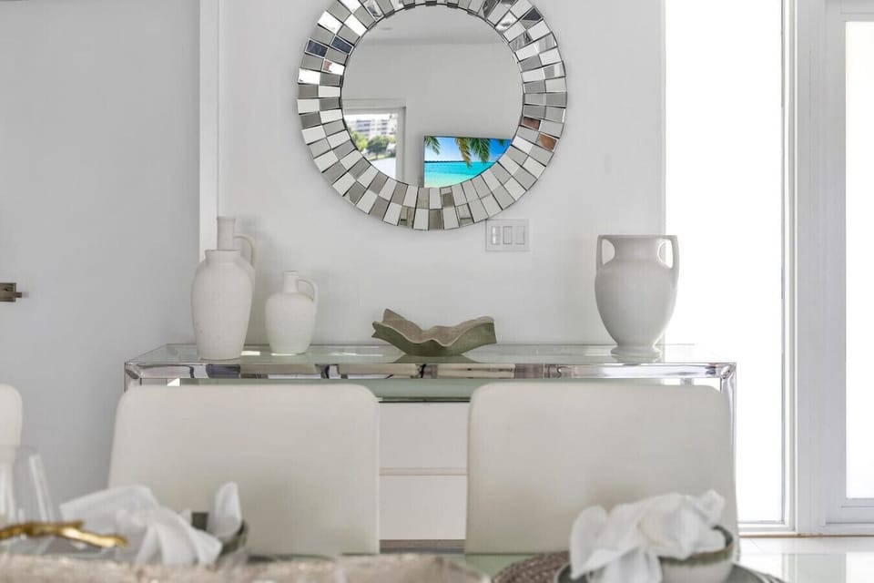 Contemporary dining area with dramatic sunburst mirror and premium ceramic accent pieces