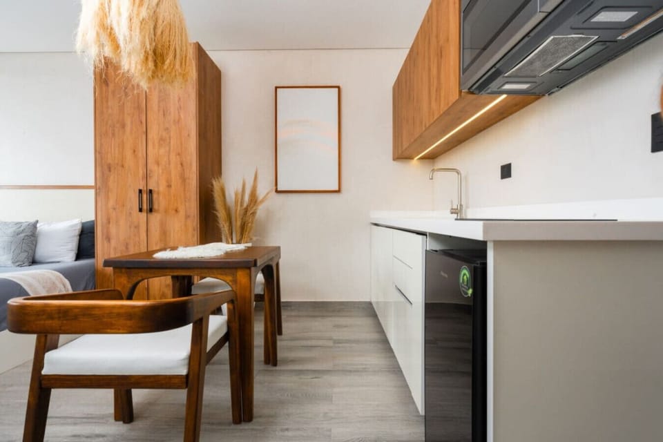Kitchen with fridge, table, and warm wood finishes.