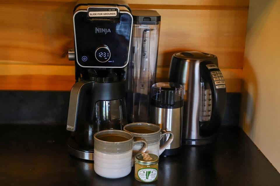 Coffee bar includes drip coffee machine, coffee bean grinder and tea kettle.
