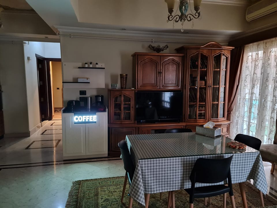 A view for the dining with a door to the balcony,a smart TV and a cofee station.