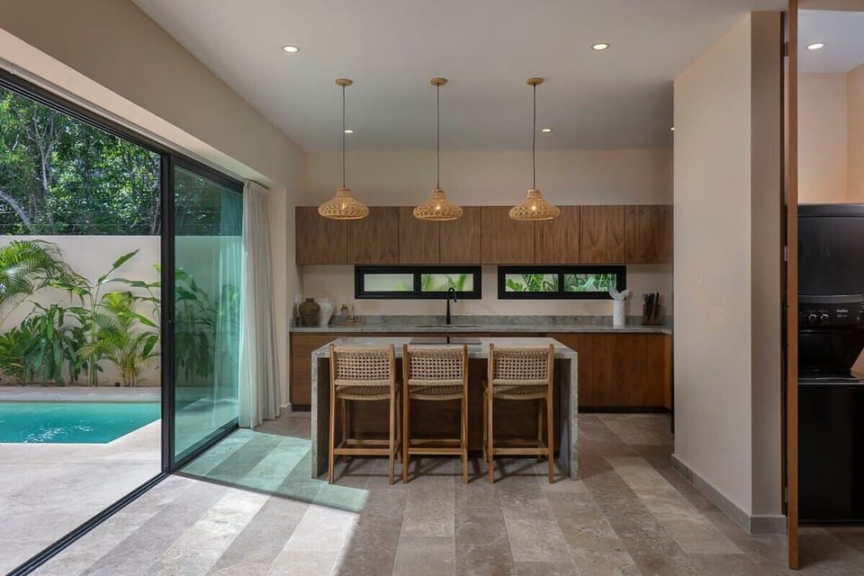 Modern and elegant kitchen. It features an impressive island with seating for three guests.
