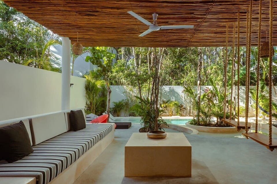 Comfortable and modern covered outdoor living room. It has a ceiling fan and innovative hammocks as part of the seating.