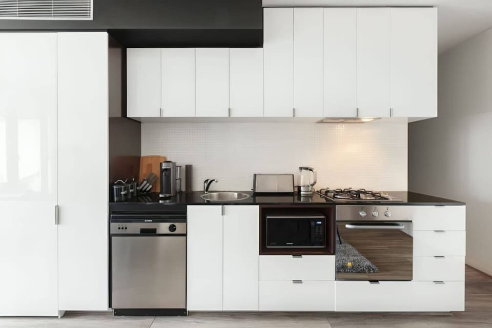 Cook with ease in the sleek, modern kitchen of apartment one featuring an oven, dishwasher, and all the essentials in an open-plan setting.