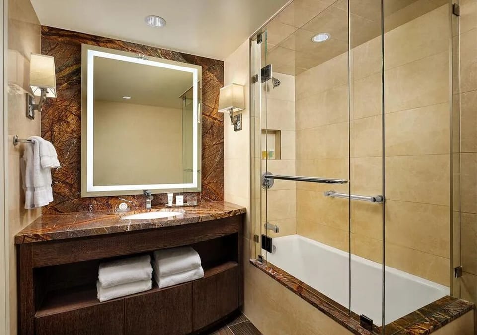 Refresh in a sleek bath-and-shower combo with warm lighting.