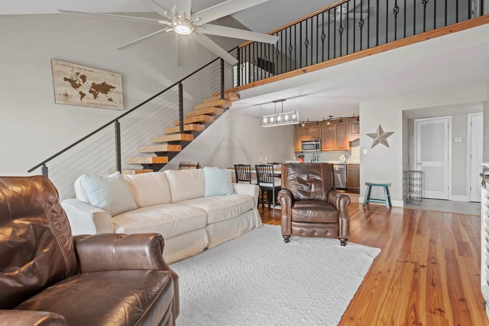 Unwind in the living room of our Cotton Bayou condo, featuring a comfortable couch and cozy recliners, perfect for relaxing after a day of coastal adventures. Enjoy modern decor, a smart TV, and a welcoming atmosphere.