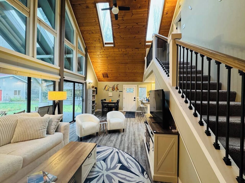 Open floor plan, wall of windows, and light coastal farmhouse style furnishings captures the unique essence of country island life in the Pacific Northwest