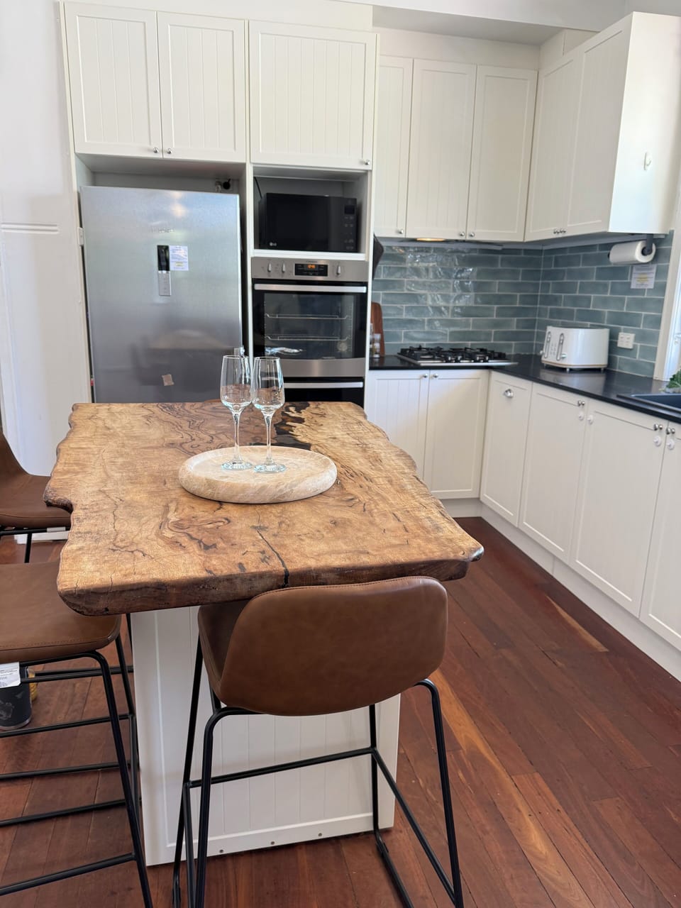 Whip up delicious meals in this beautifully appointed kitchen! Complete with a full-sized refrigerator, oven, stove, ample counter space, and a unique live-edge wooden island for dining or entertaining.