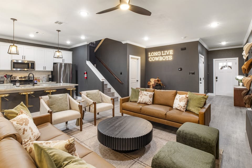 The living room opens seamlessly to the elegant kitchen and showcases the staircase.
