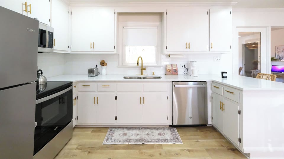 Kitchen fully stocked with plateware, cookware, utensils, coffee and tea maker