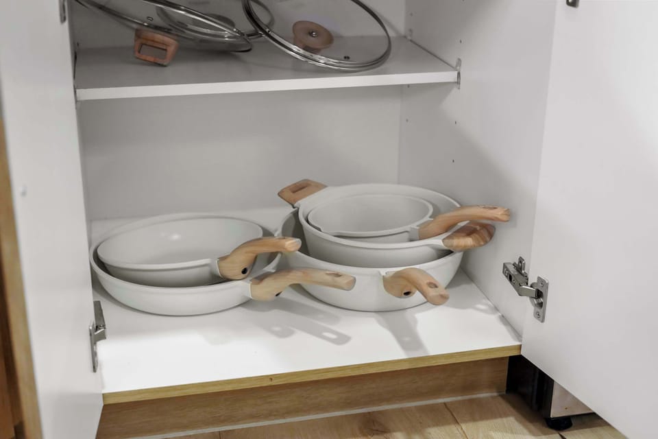 Cabinet with plates, bowls, and cookware — perfect for long-term stays, offering everything needed for comfortable home-style cooking.
