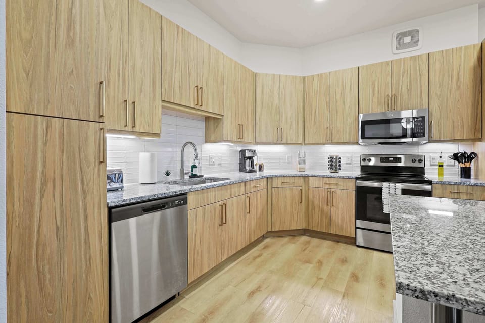 Modern L-shaped kitchen designed for extended stay guests, featuring full-size appliances, dishwasher, and generous counter space.