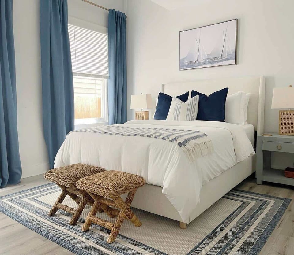 Bright and airy, the bedroom’s bed is piled with pillows, enhancing the cozy, coastal atmosphere.