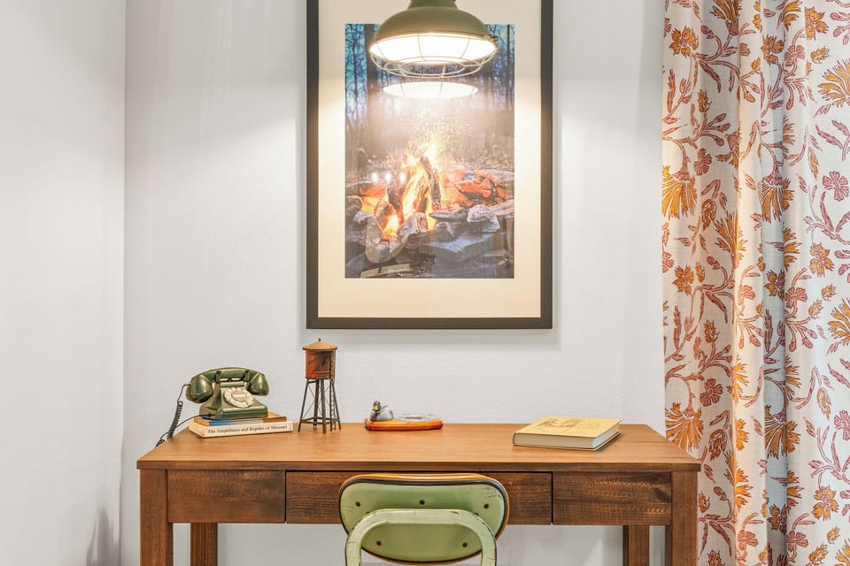 - Step into a comfortable work nook with vintage charm and thoughtful touches
- Retro phone, campfire art, and antique décor invite creativity and nostalgia
- Natural wood tones and warm lighting create a calming spot for reflection