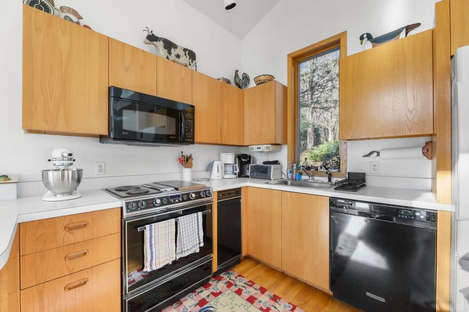 Contemporary kitchen with wood cabinetry, full-size appliances, and a scenic window over the sink.