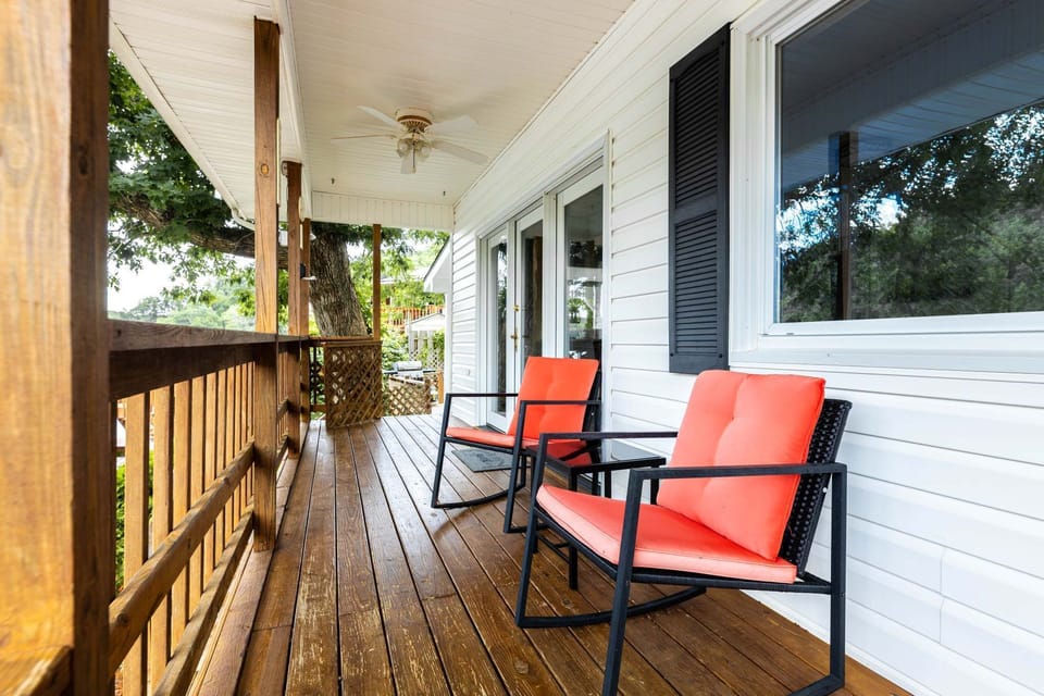 Relax with ake views on cozy red-cushioned rocking chairs under a shaped porch
