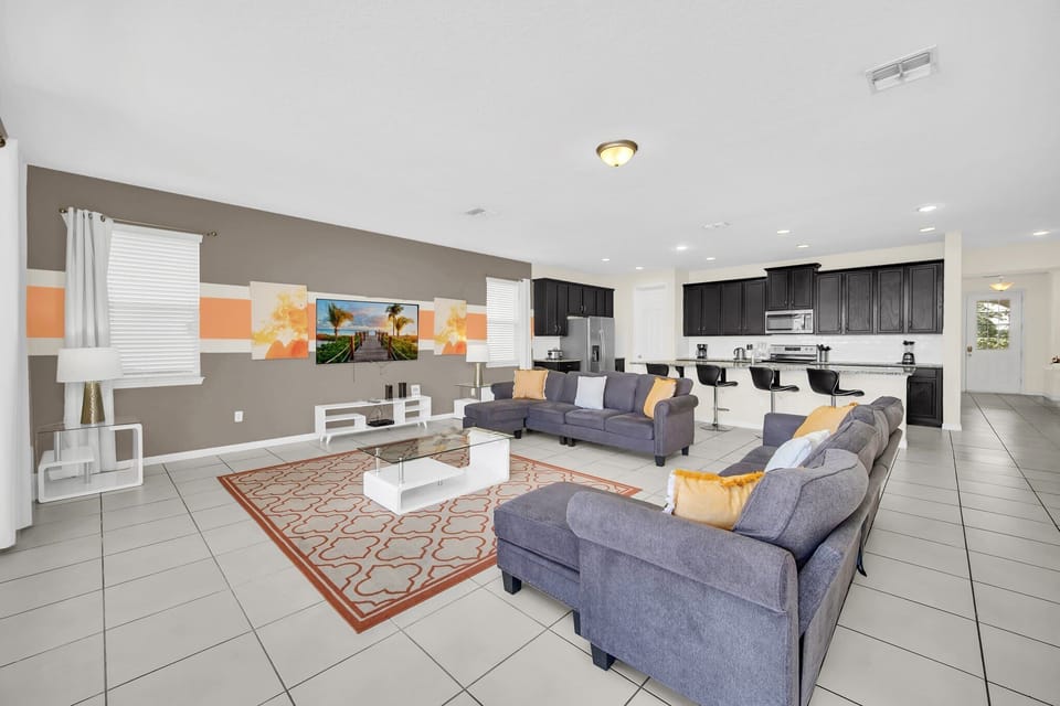Spacious open-concept living area with plush seating, vibrant decor, and a large flat-screen TV. Perfectly connected to the modern kitchen and dining spaces, it’s ideal for entertaining and relaxing with family and friends.