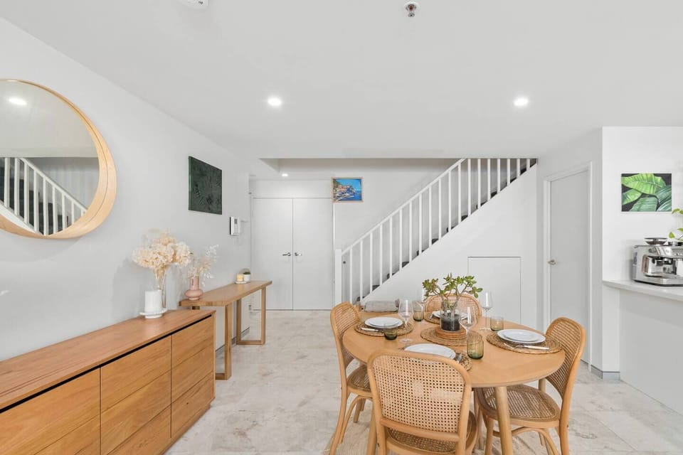 Savour meals at the elegant four-seater table with vintage charm, adding a cosy contrast to the apartment’s bright background.
