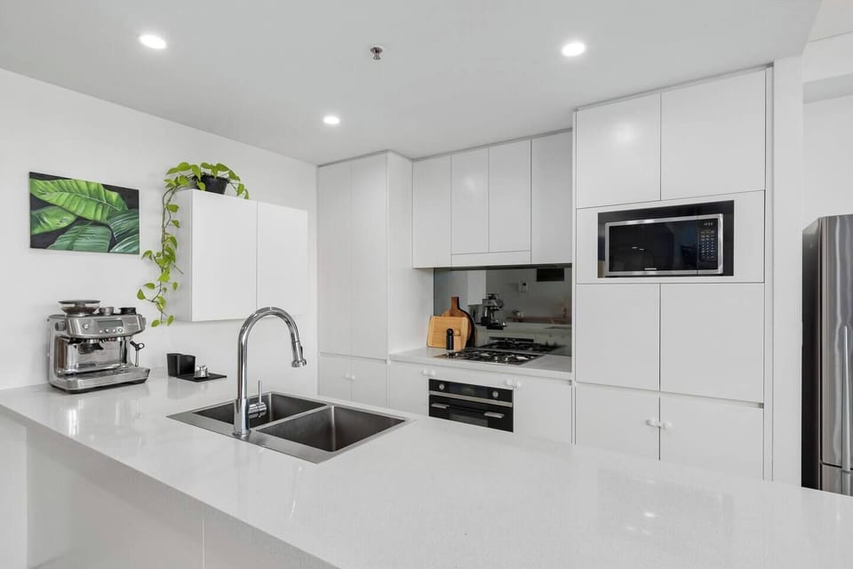 Experiment with flavours in this sleek, modern kitchen boasting ample counter space, a coffee machine, and premium appliances like an oven—perfect for your culinary adventures.