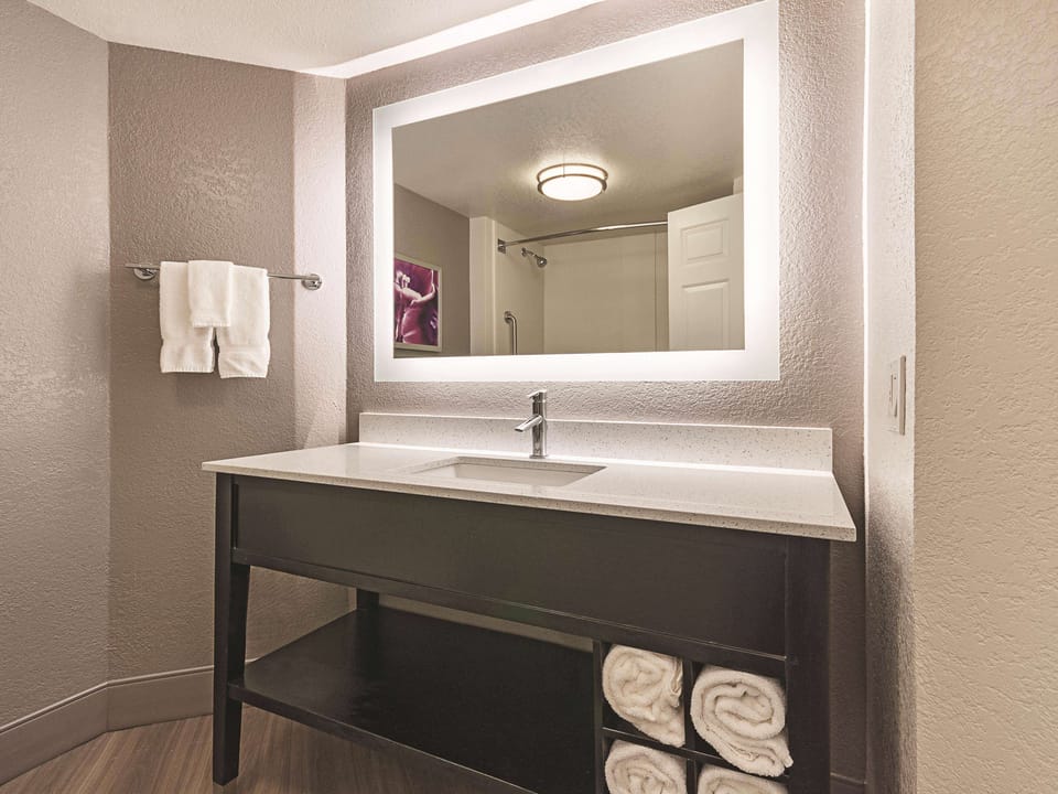 Refresh at a sleek vanity with glowing mirror and fluffy towels.
