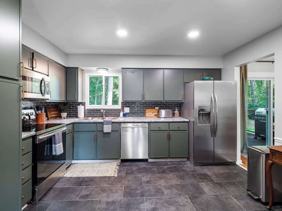 Modern kitchen w/ stainless steel appliances, sleek cabinetry & large window above the sink