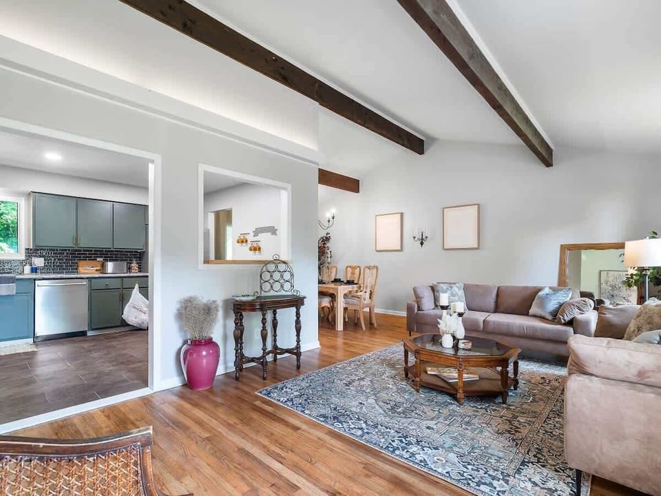 Open living room w/ wood beam ceilings, comfy seating & view into the kitchen