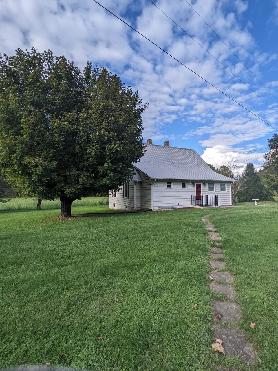 Expansive yard with mature trees and a peaceful path leading to the charming back entrance.