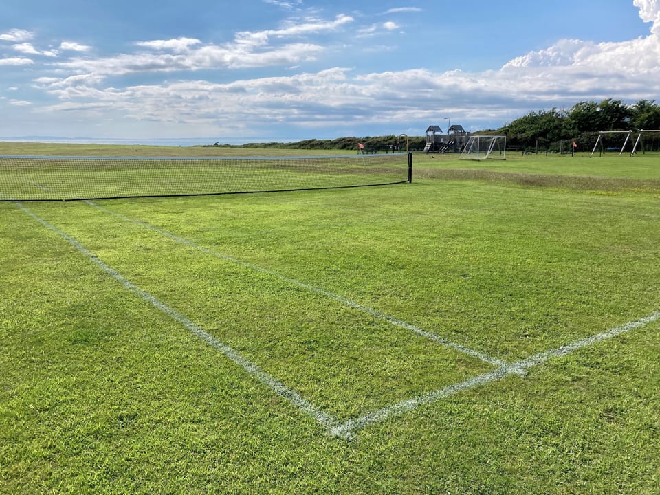 Grass tennis court, bats and balls supplied