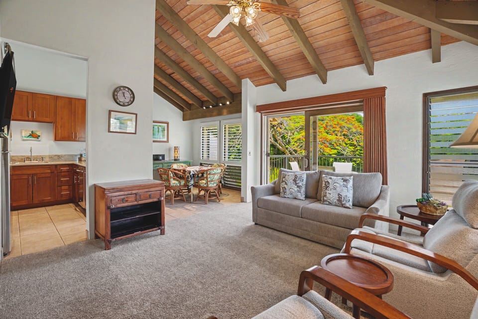 Unwind in your open-concept living space, where soaring wood-beamed ceilings and lush tropical views invite you to relax. The kitchenette, cozy seating, and island breeze create your perfect retreat.
