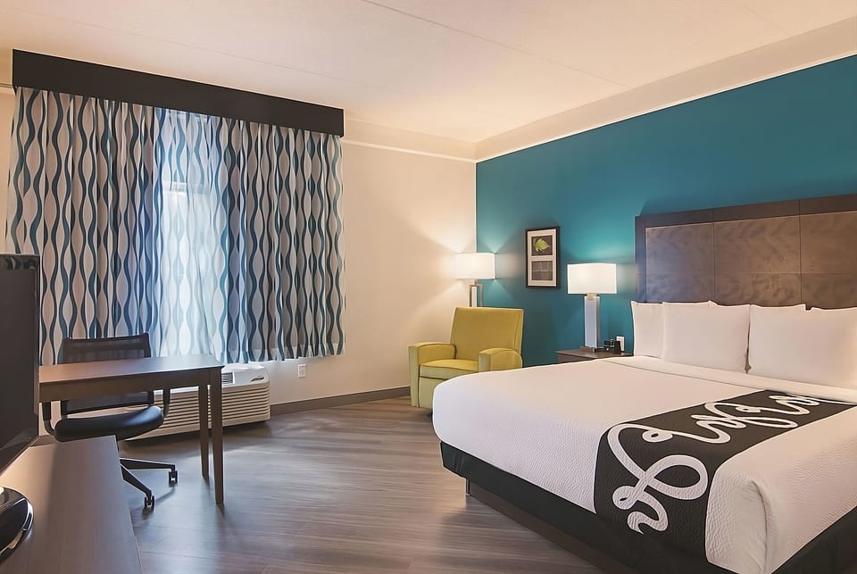 Relax in a sunlit room with desk, TV, and plush bed.