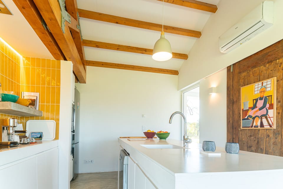 Modern open-plan kitchen with yellow tile accents and wooden beams — Villa do Pinheiro, holiday villa in Grândola