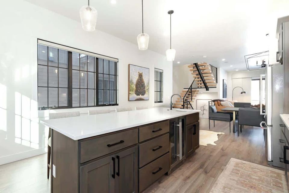 - Spacious island with quartz counters and deep storage faces the open living area
- Pendant lighting and bar seating make it ideal for chats, snacks, or prep
- Beautiful blend of rustic tones and airy design throughout