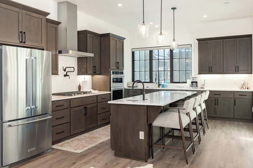 - Cook up memories in this spacious kitchen with stainless steel appliances and island bar
- Rich wood cabinetry and modern lighting blend style with function effortlessly
- Perfect for prepping meals or gathering with friends