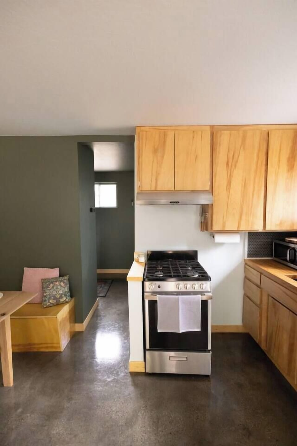 The kitchen features a gas oven with four stovetop burners and range exhaust.