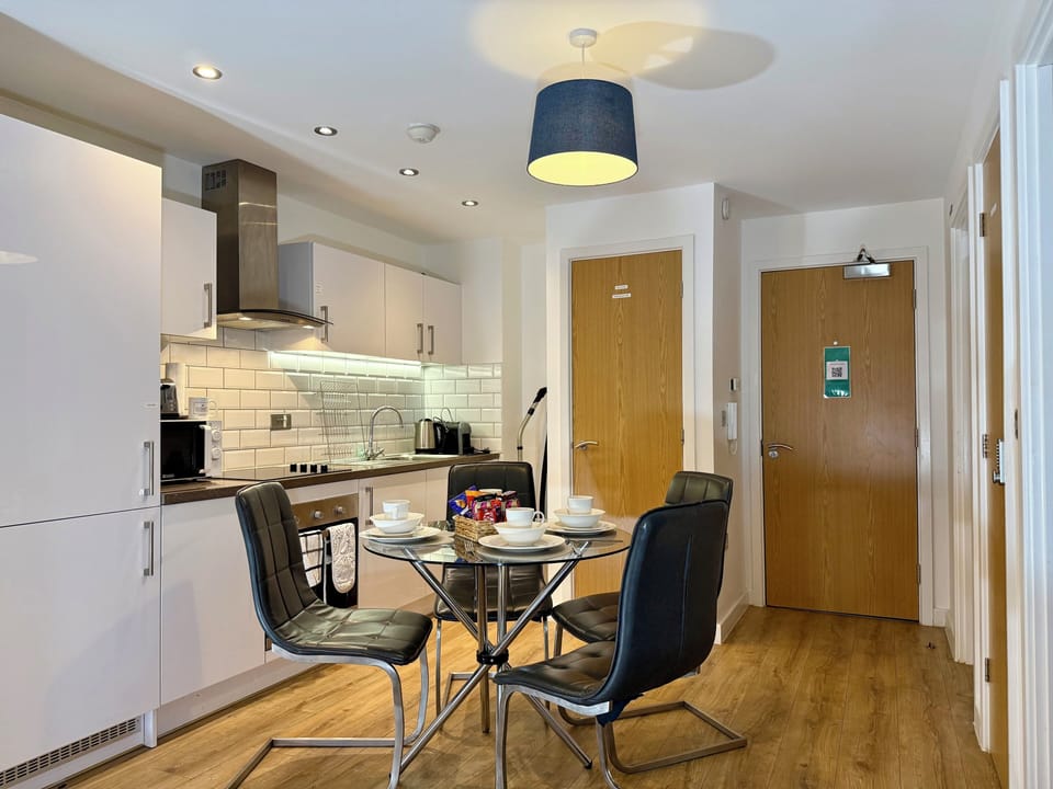 Modern open-plan kitchen and dining area featuring a fully equipped kitchen and a stylish dining table set for four, perfect for enjoying meals together