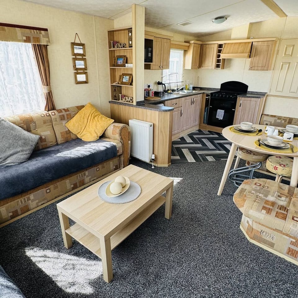 Bright open-plan space with a cozy sofa, coffee table & dining area—perfect for unwinding in your Skegness holiday home.