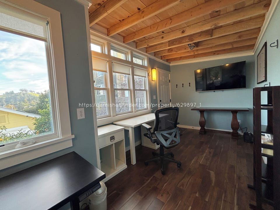 Studio/office with 2 desks, small bookshelf, and big screen TV
