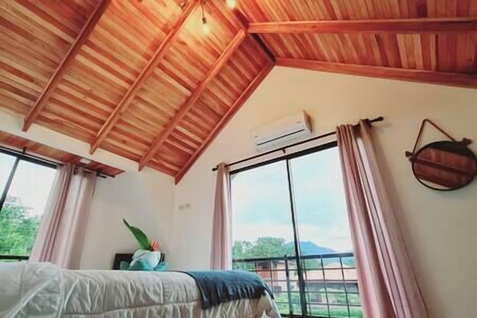 Master room: wooden ceiling and glass doors toward the volcano-view terrace.