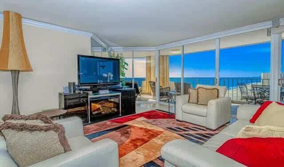 The living room has views of the sunset and access to a spacious balcony overlooking the ocean.