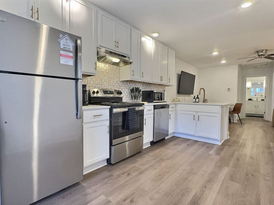 This kitchen features elegant white cabinetry complemented by chic gold hardware, offering a fresh and contemporary look.