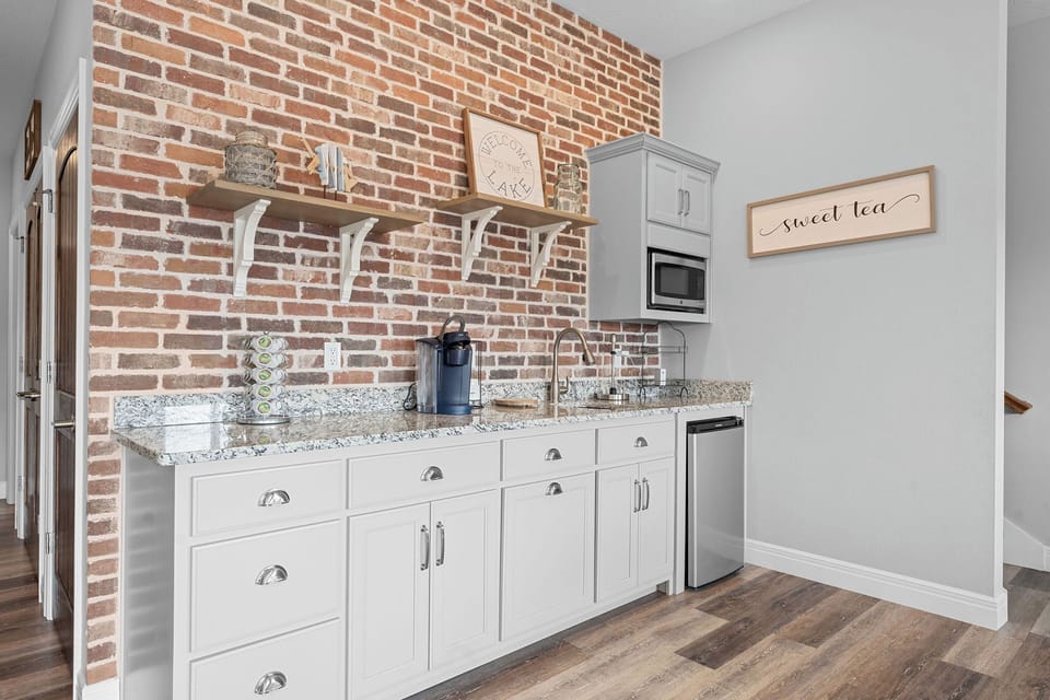 - Charming kitchenette featuring exposed brick, open shelving, and modern finishes for a cozy, rustic vibe
- Equipped with a Keurig, microwave, mini fridge, and essentials for your drink station
- Perfect for coffee breaks or midnight snacks