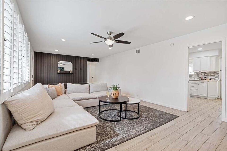 Bright and open living area with designer furnishings, glass table with seating, and a Smart TV.