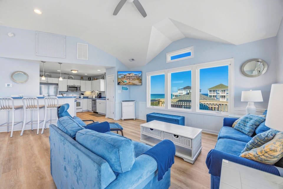 Sink into plush blue seating and soak in stunning sea views through expansive windows. High ceilings and coastal-chic décor create your breezy, light-filled retreat.