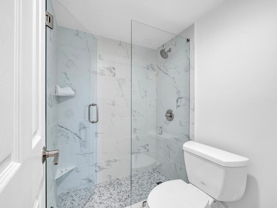 Step into your luxurious marble-wrapped shower sanctuary, where elegant glass doors open to reveal a spa-like retreat perfect for unwinding after your adventures.