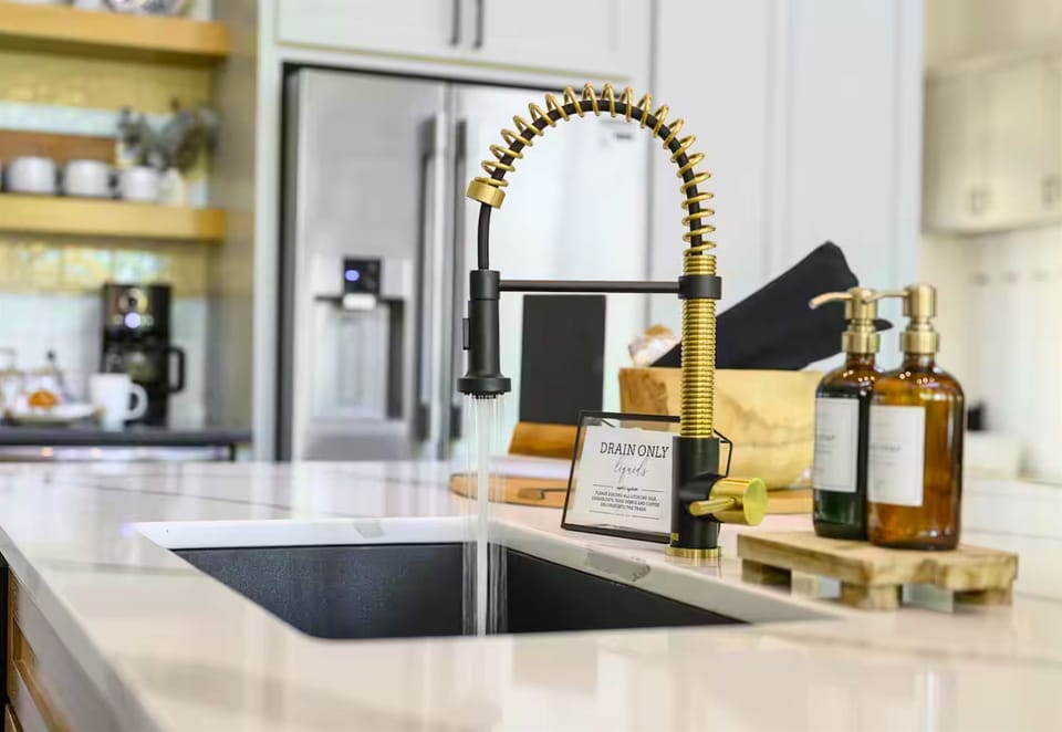 This sleek kitchen sink, complete with a brushed gold faucet and stylish countertop essentials, turns even the simplest tasks into a luxurious experience.