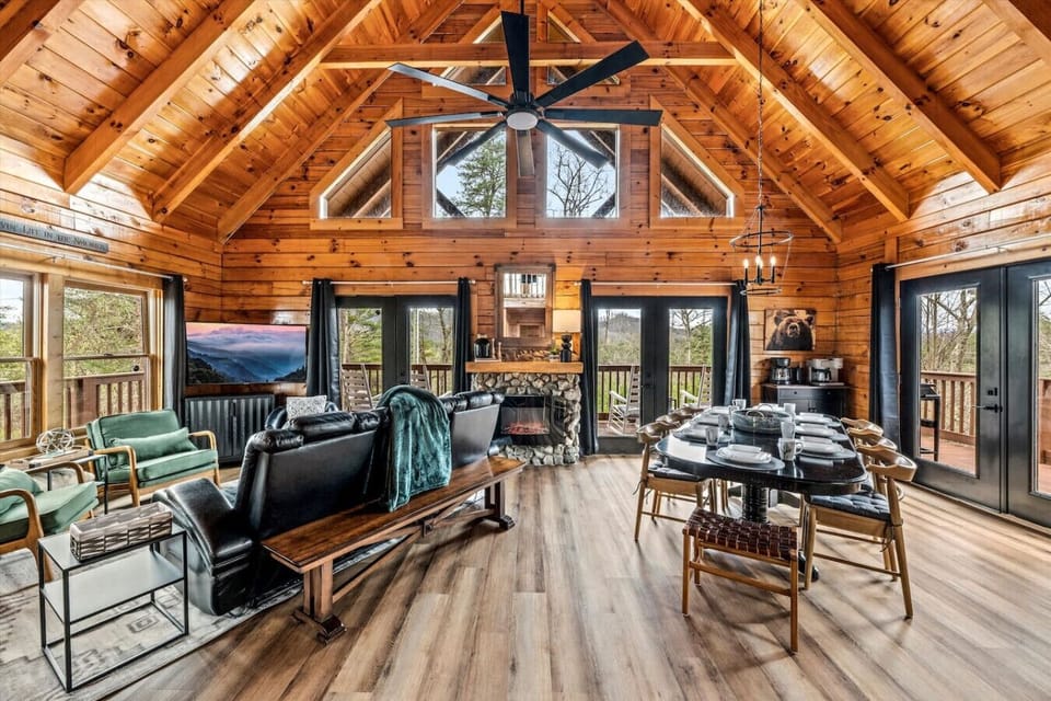 The heart of the cabin features a spacious layout with a fireplace, vaulted ceilings, living area,and dining space perfect for sharing meals and stories.