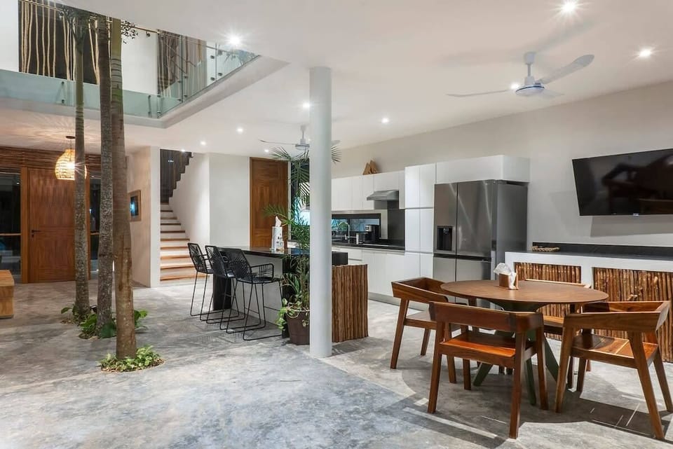 Unique design on the ground floor. The space is integrated with a dining area, kitchen, and natural trees growing in the center, extending up to the second floor.