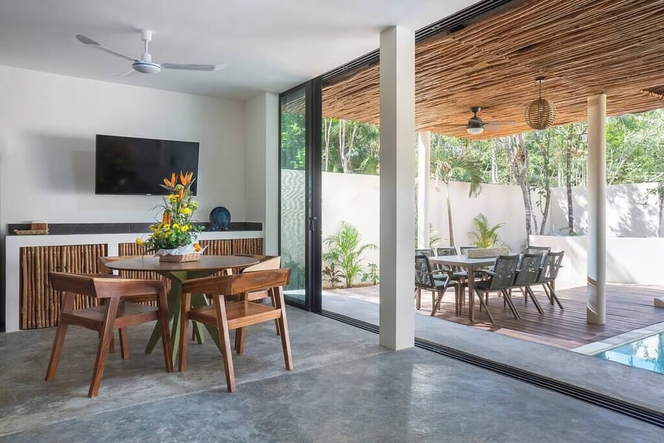 Modern and elegant dining room. It has a TV, ceiling fan, and windows connecting to the courtyard.