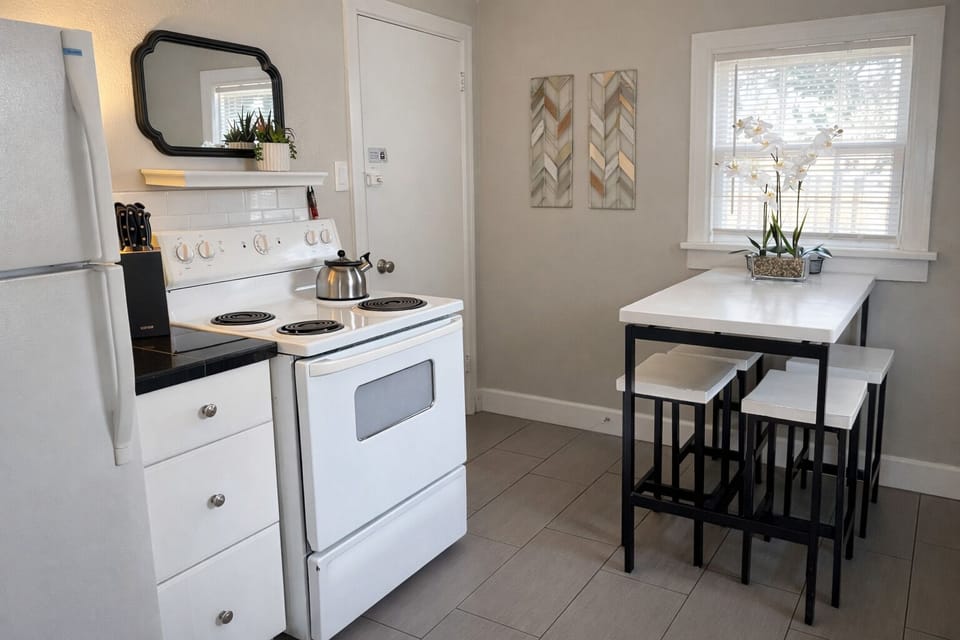 Your fully equipped kitchen awaits with everything needed for home cooking - stove, fridge, and cozy dining nook for morning coffee together.